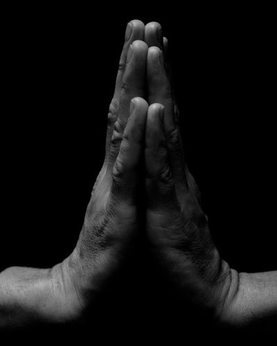 Close-up of a person's hands in a meditative gesture.